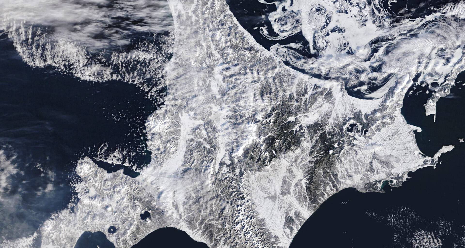 A satellite image shows snow blanketing Hokkaido, Japan, with sea ice swirling just north of the island.