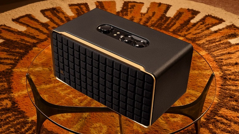The JBL Authentics 500 smart speaker on a glass table on a colorful carpet.