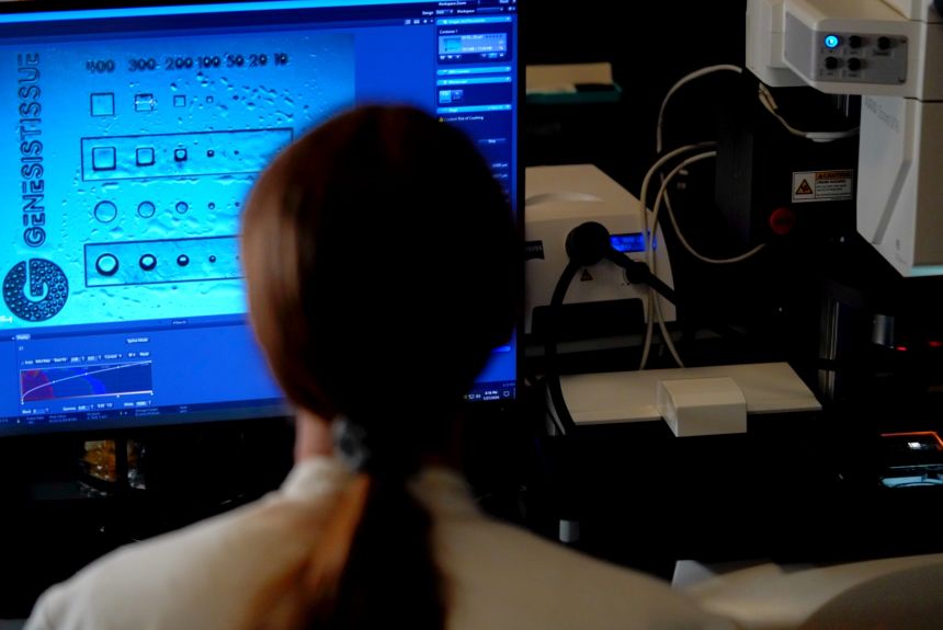 Kianna Young, a biomedical engineer at GenesisTissue, examines the resolution of a 3D-printed biomaterial sample under a microscope.