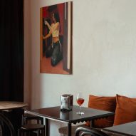 Bar interior with wooden seating, glass pendant light shades and painting on the wall