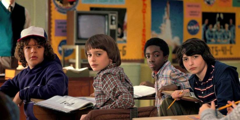 The kids sitting at school desks look back in a classroom in the MADMAX episode of Stranger Things.