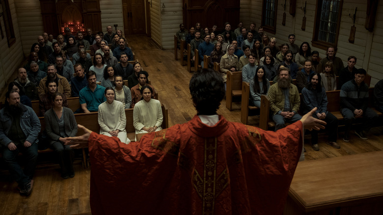 Father Paul raising his arms while leading mass in Midnight Mass (2021)