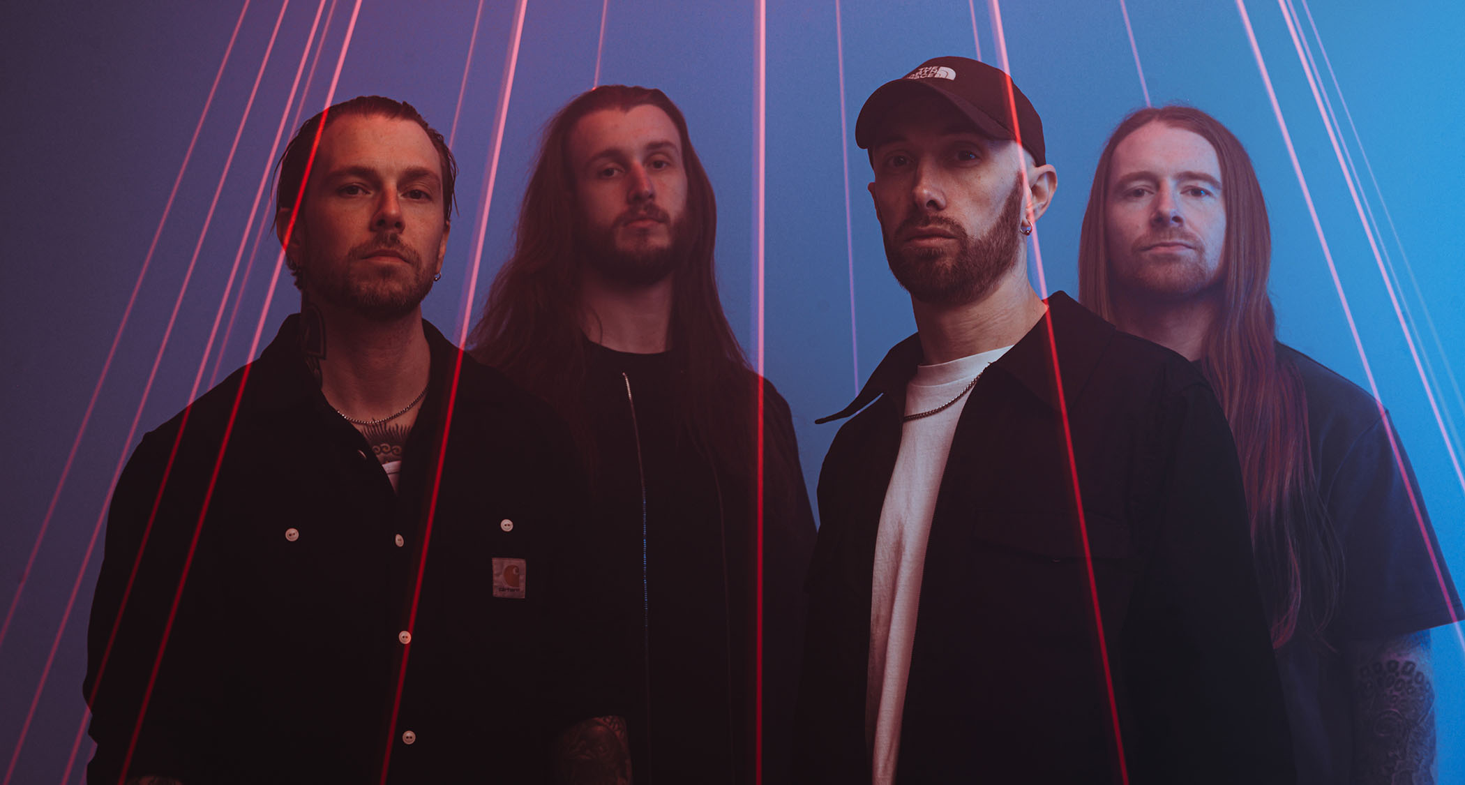 A portrait of UK metal stalwarts Sylosis, pictured under an array of laser beams [L-R] Bassist Ben Thomas; guitarist Conor Marshall; frontman/guitarist Josh Middleton; drummer Ali Richardson.