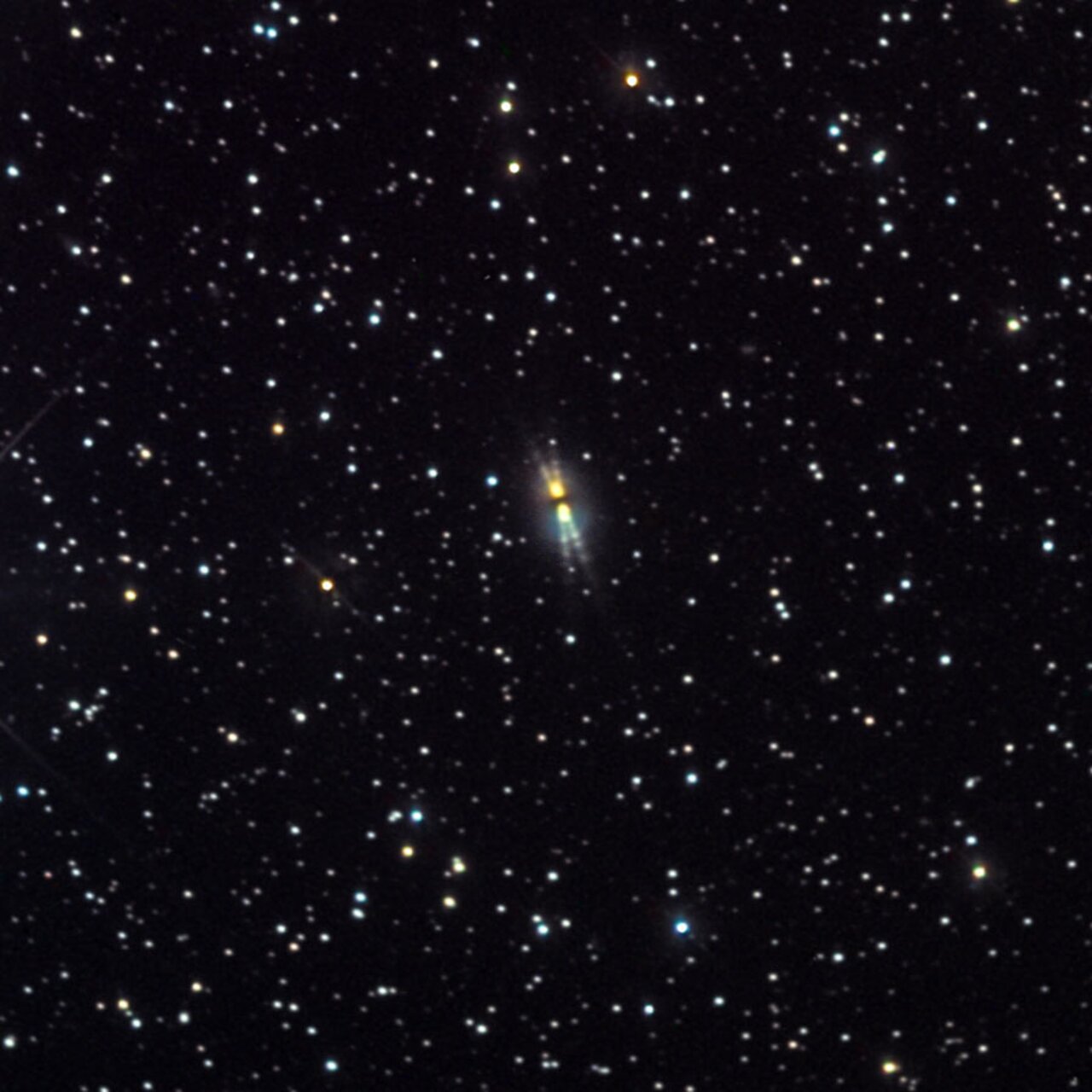 A dense field of stars with a bright, elongated galaxy in the center, possibly captured by Hubble, surrounded by numerous smaller stars against a black background, evoking the grandeur of cosmic evolution and dying sun stars.