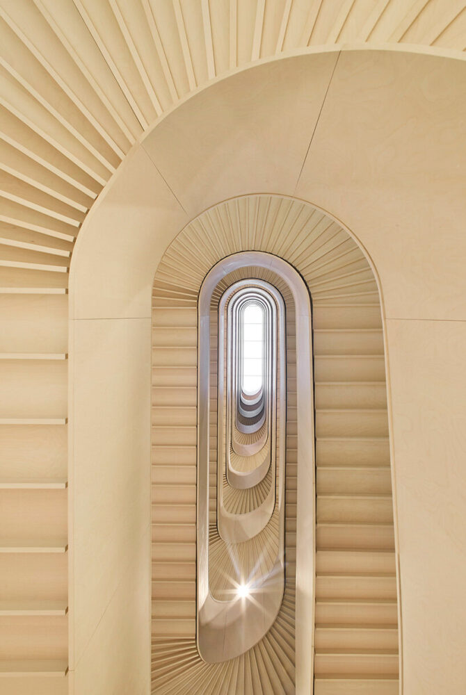 a sculpted timber staircase spirals through the atrium