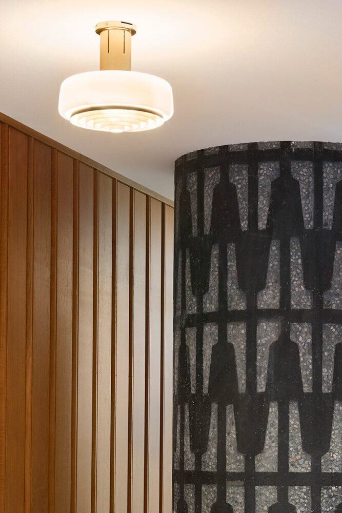 historic terrazzo column and vertical timber paneling highlight material continuity across old and new
