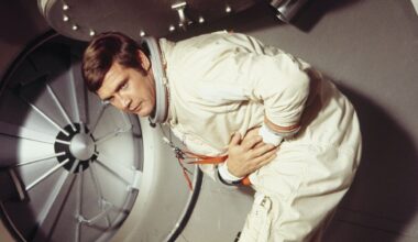 A man in space holding his stomach.