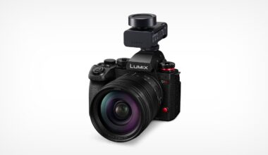 A black Panasonic LUMIX S1 camera with a large lens and an external microphone mounted on top, displayed against a plain white background.