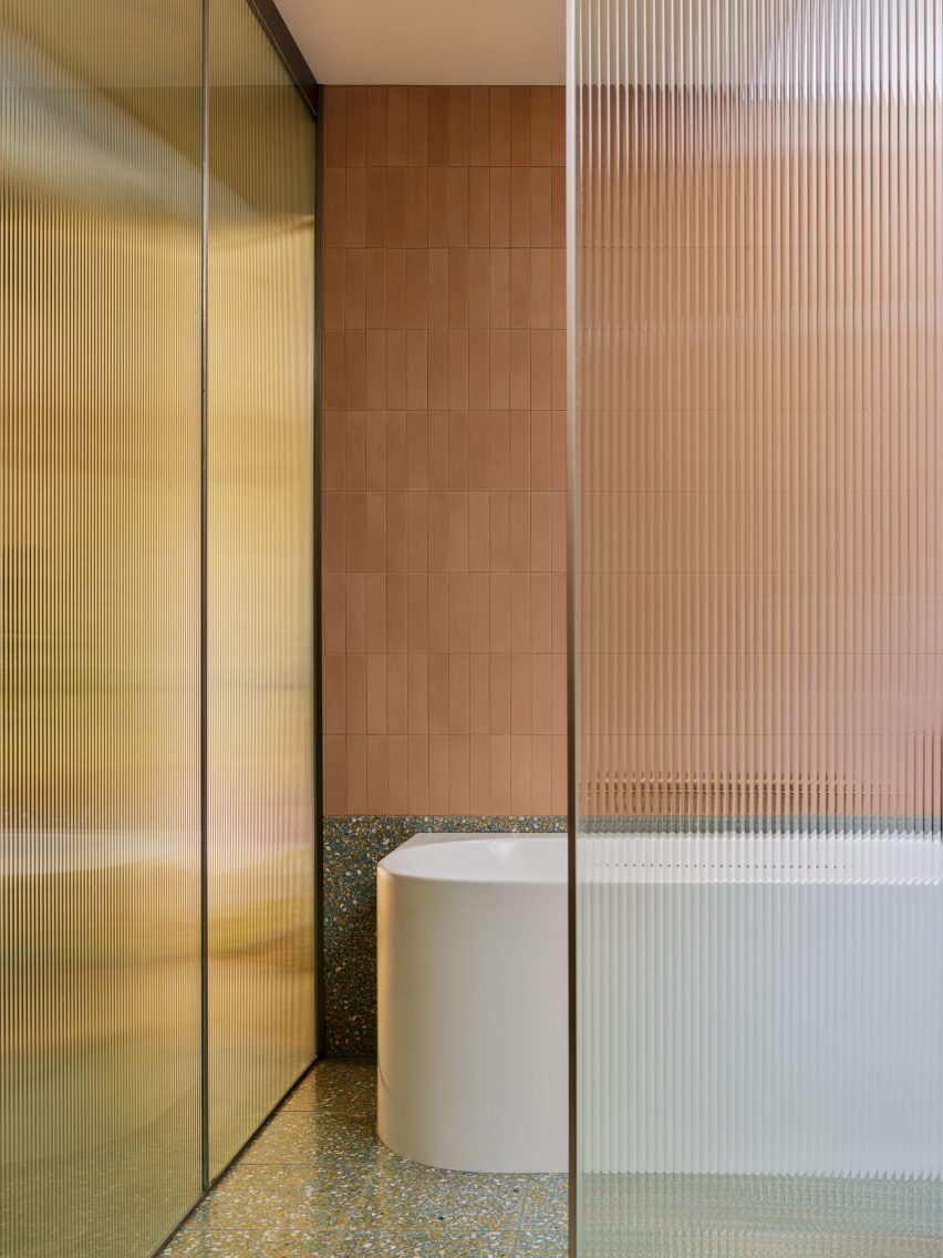 Bathroom with earth-hued tiles, terrazzo and fritted glass