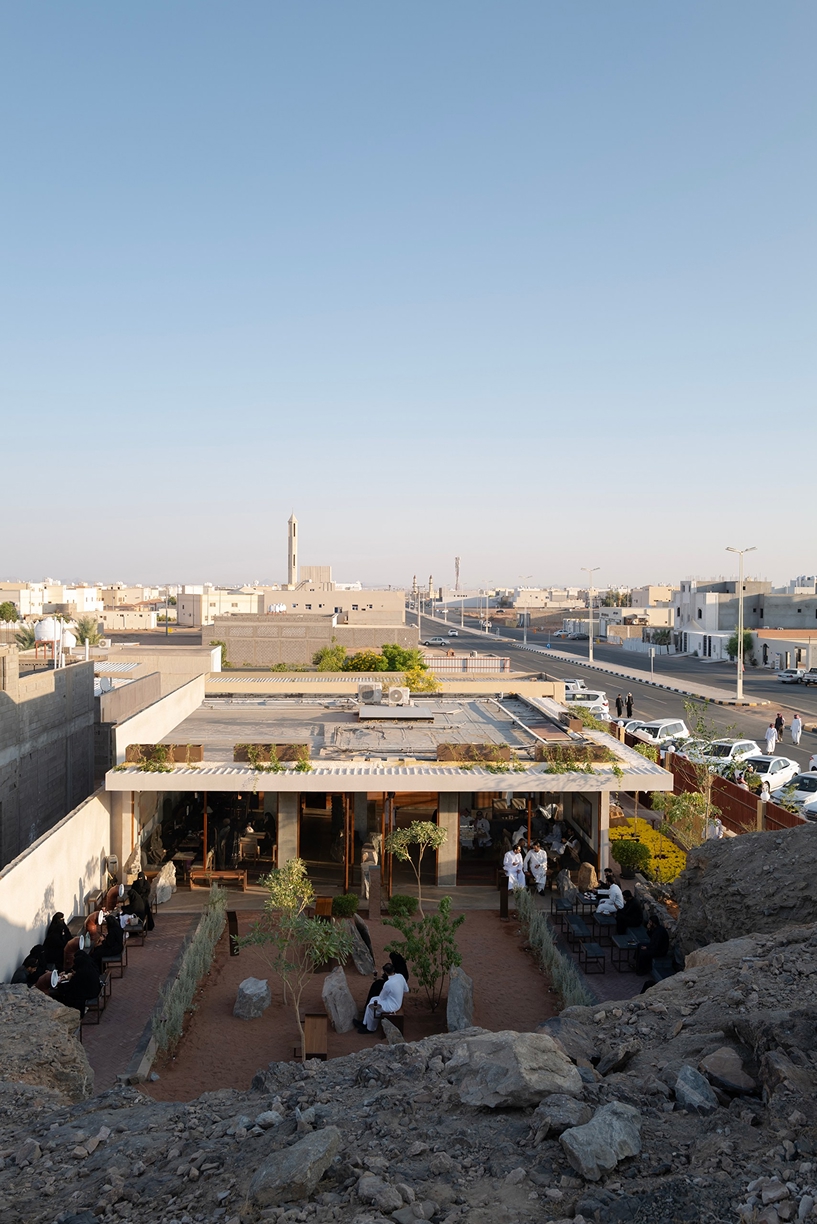 open planted courtyard organizes a café carved directly into rock in saudi arabia
