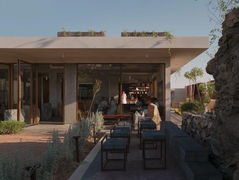 open planted courtyard organizes a café carved directly into rock in saudi arabia