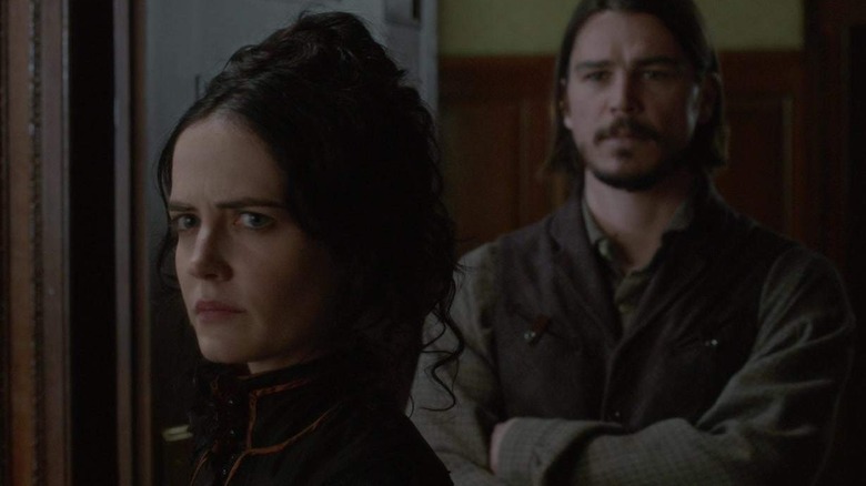 Vanessa in dark top looking severe with Ethan crossing his arms behind her in Penny Dreadful