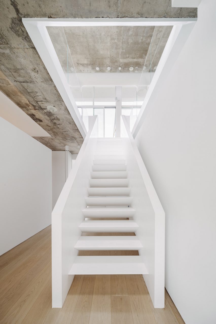 A central stairwell wrapped with glass balustrades on the upper level
