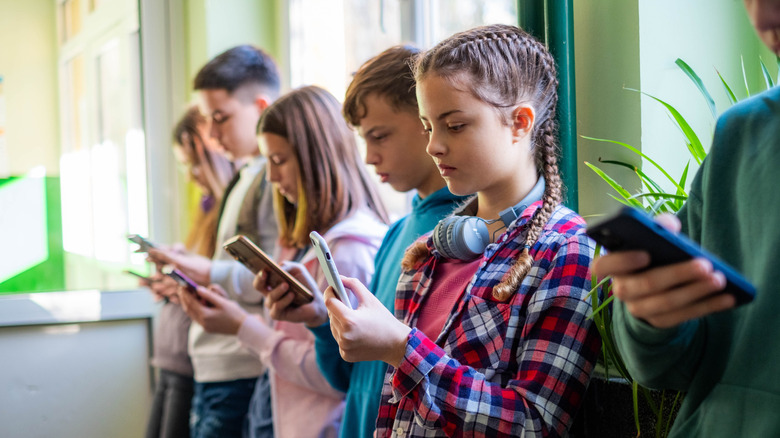 Children standing in a line using smartphones