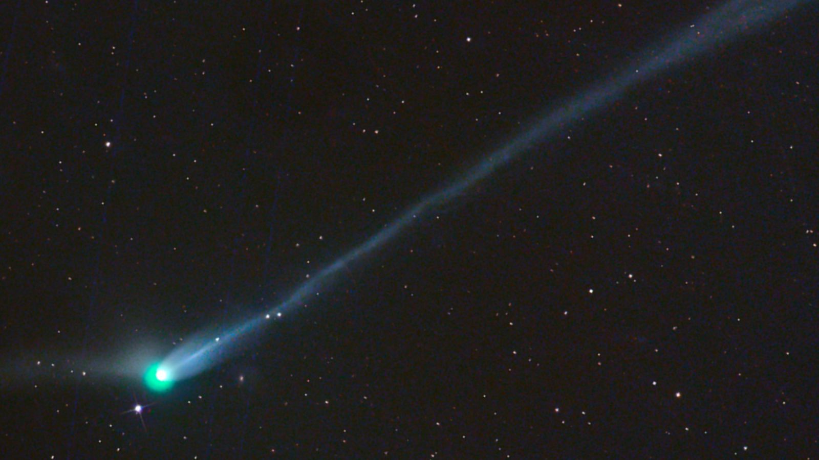 A photo of the green comet with a long tail in the night sky