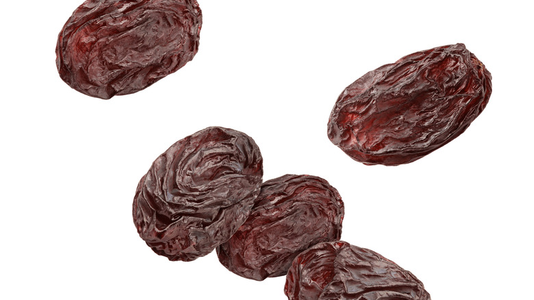 Raisins falling against a white background