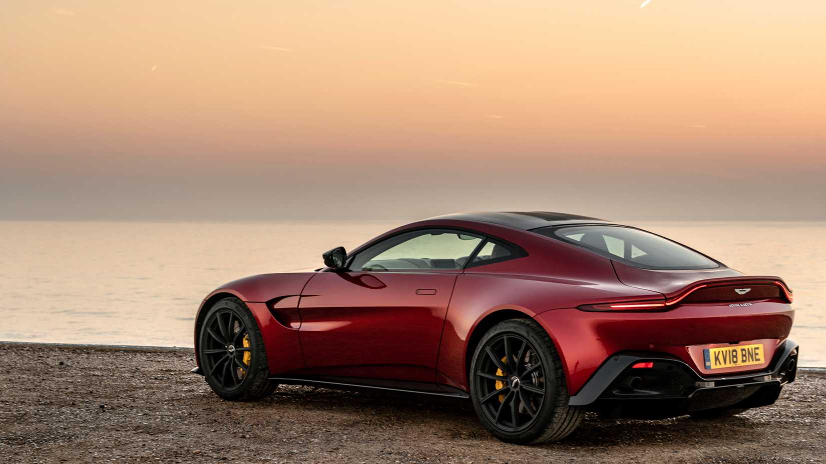 Red Aston Martin Vantage 550 parked by a still lake