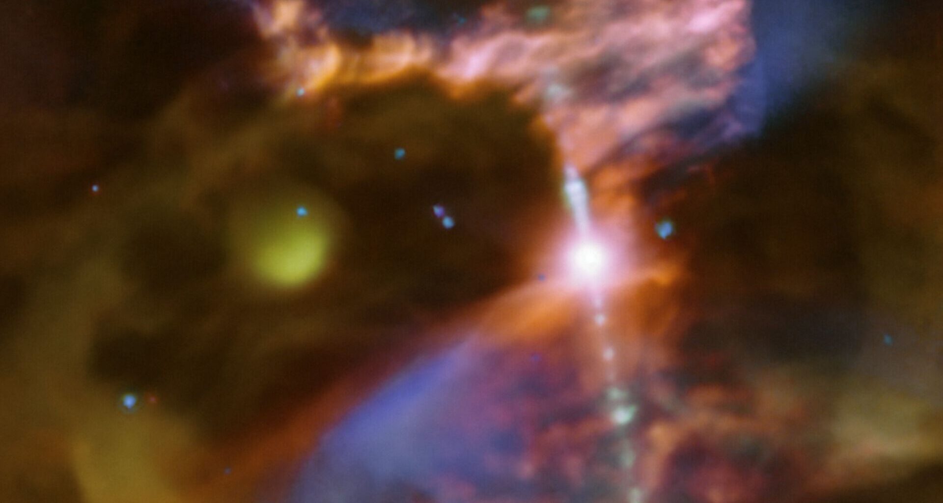 A blurry swirl of blue and yellow and red gas are seen in this image with a bright dot of light in the center