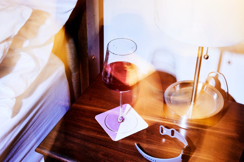 blurry wine and fitness tracker on bedside table blurry wine and fitness tracker on bedside table