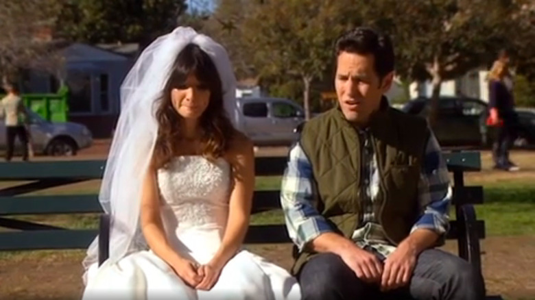 Shauna Malwae-Tweep sitting on bench in wedding dress next to Bobby Newport