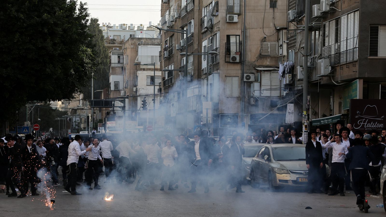 Ultra-Orthodox Jews react to a stun grenade thrown by Israeli police in Bnei Brak. Pic: Reuters