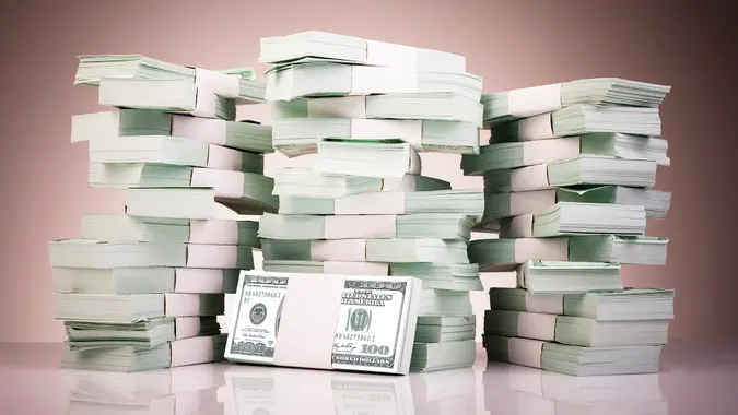 Pile of money stacked on reflective surface.