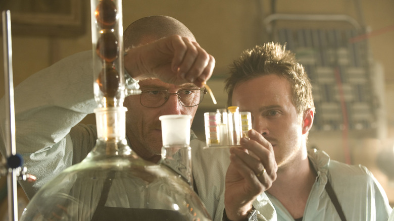 Jesse Pinkman watching Walter White, both of them wearing white lab coats in 