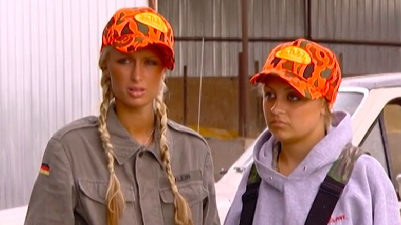 Paris Hilton with orange hat standing next to Nicole Richie with orange hat in The Simple Life