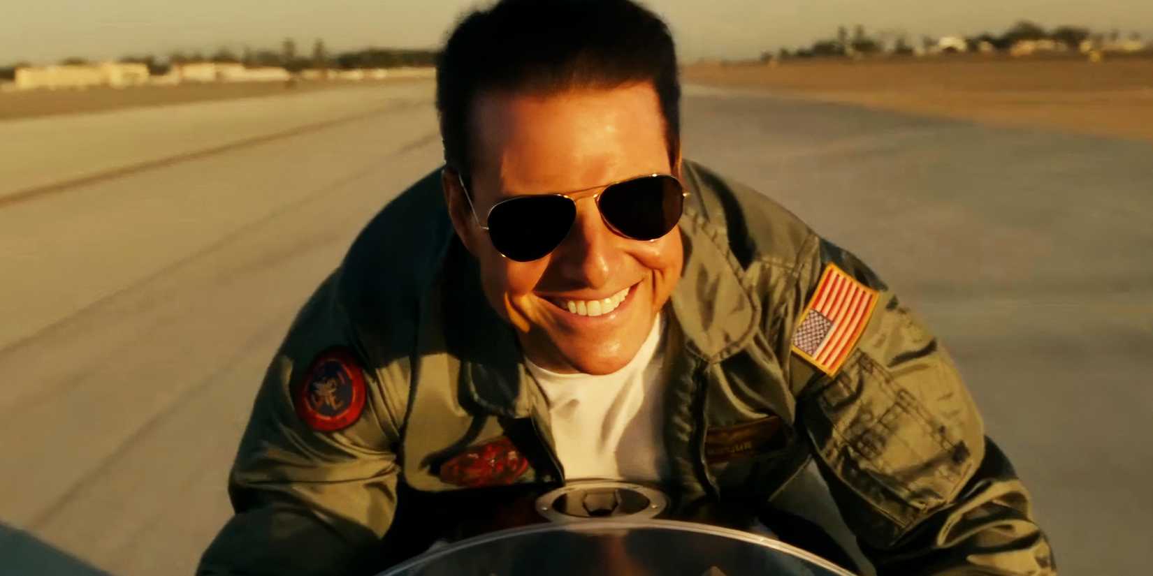 Tom Cruise smiling while driving a motorcycle in Top Gun Maverick