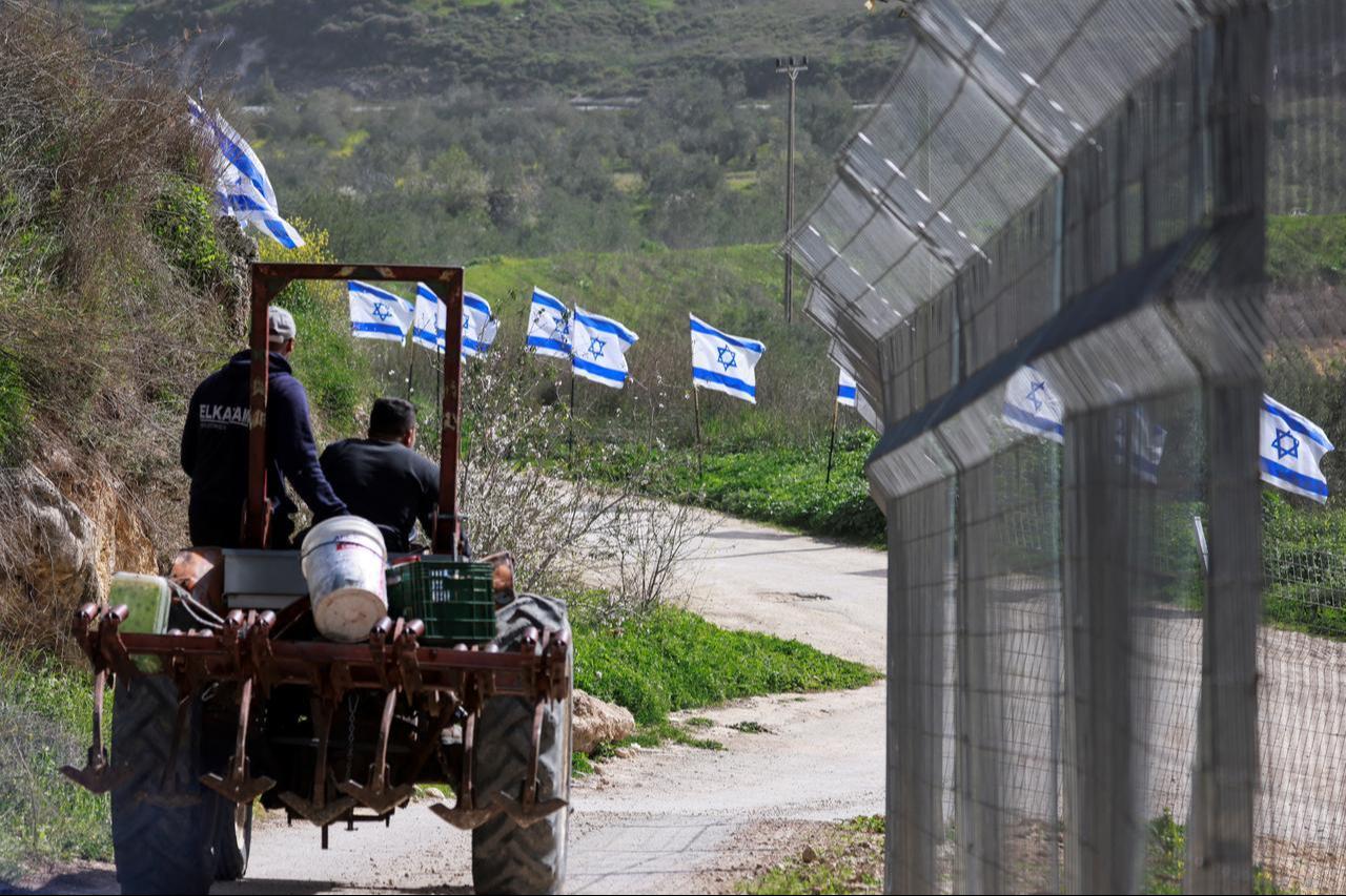 Palestinian farmers from the village of Burqa, drive their tractor past a fence decorated with Israeli flags installed by Jewish settlers after they announced their control over the Al-Masoudiya Ottoman era train station, in West Bank on February 15, 2026. (AFP Photo)