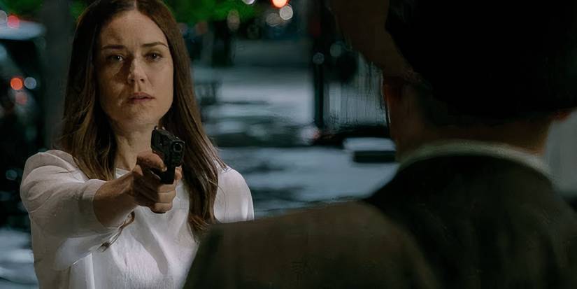 Liz pointing a gun at Red in the street, just before she is killed, in The Blacklist season 8 finale.