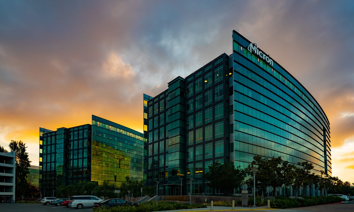Micron Technology building with company's logo on top   and the sun setting behind.