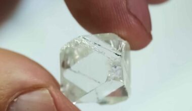 Synthetic diamond crystal held between fingers, symbolizing US-Japan plans to invest $550B to reduce reliance on China
