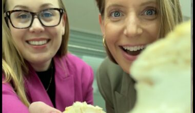 Two women hold up spongy white materials to the camera, one woman wears glasses and a pink blazer and the other has a gold hoop earring