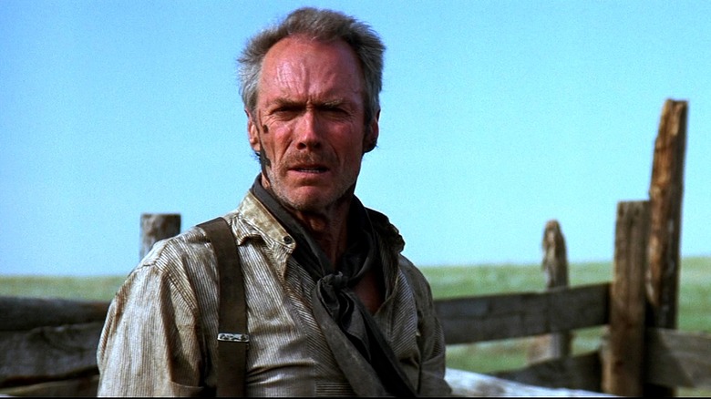 Clint Eastwood as Will Munny standing near a fence outdoors in Unforgiven