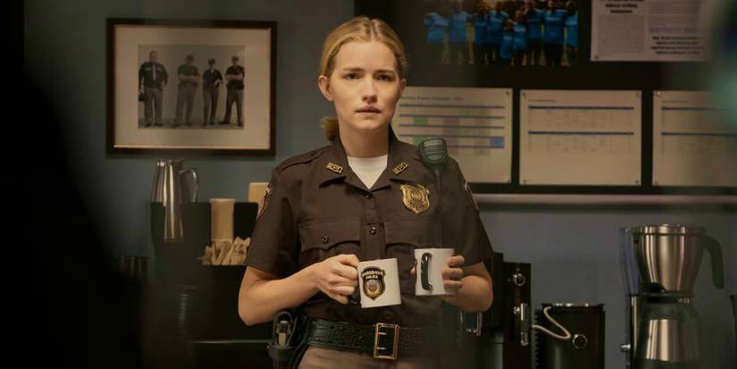 Willa Fitzgerald as Roscoe holding coffee cups in Reacher season 1.