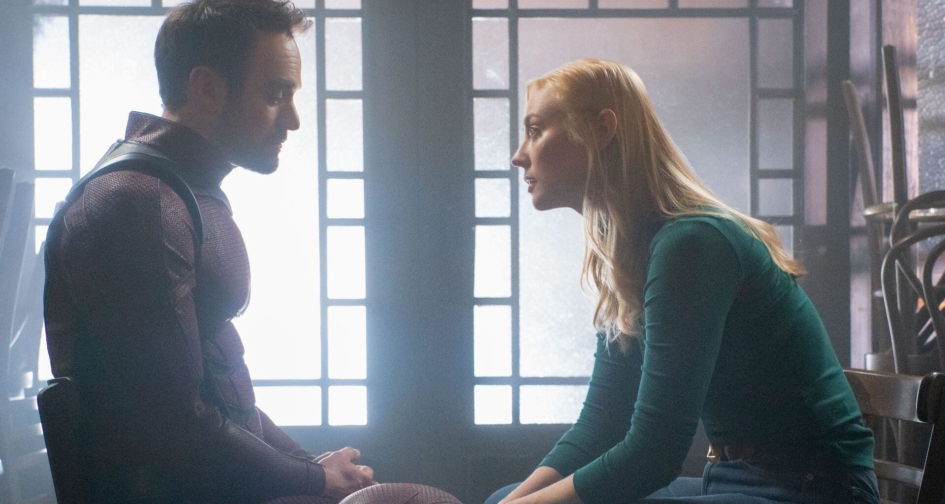 An unmasked Matt Murdock (Charlie Cox) sitting across from Karen Page (Deborah Ann Woll) in Daredevil: Born Again season 2