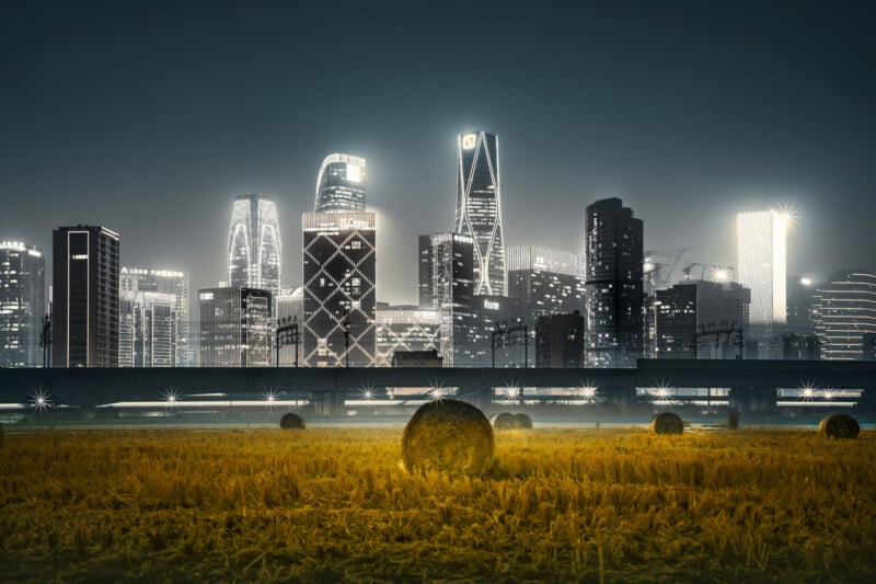 A futuristic city skyline with glowing skyscrapers stands behind a rural field with hay bales at night, blending urban and agricultural landscapes.