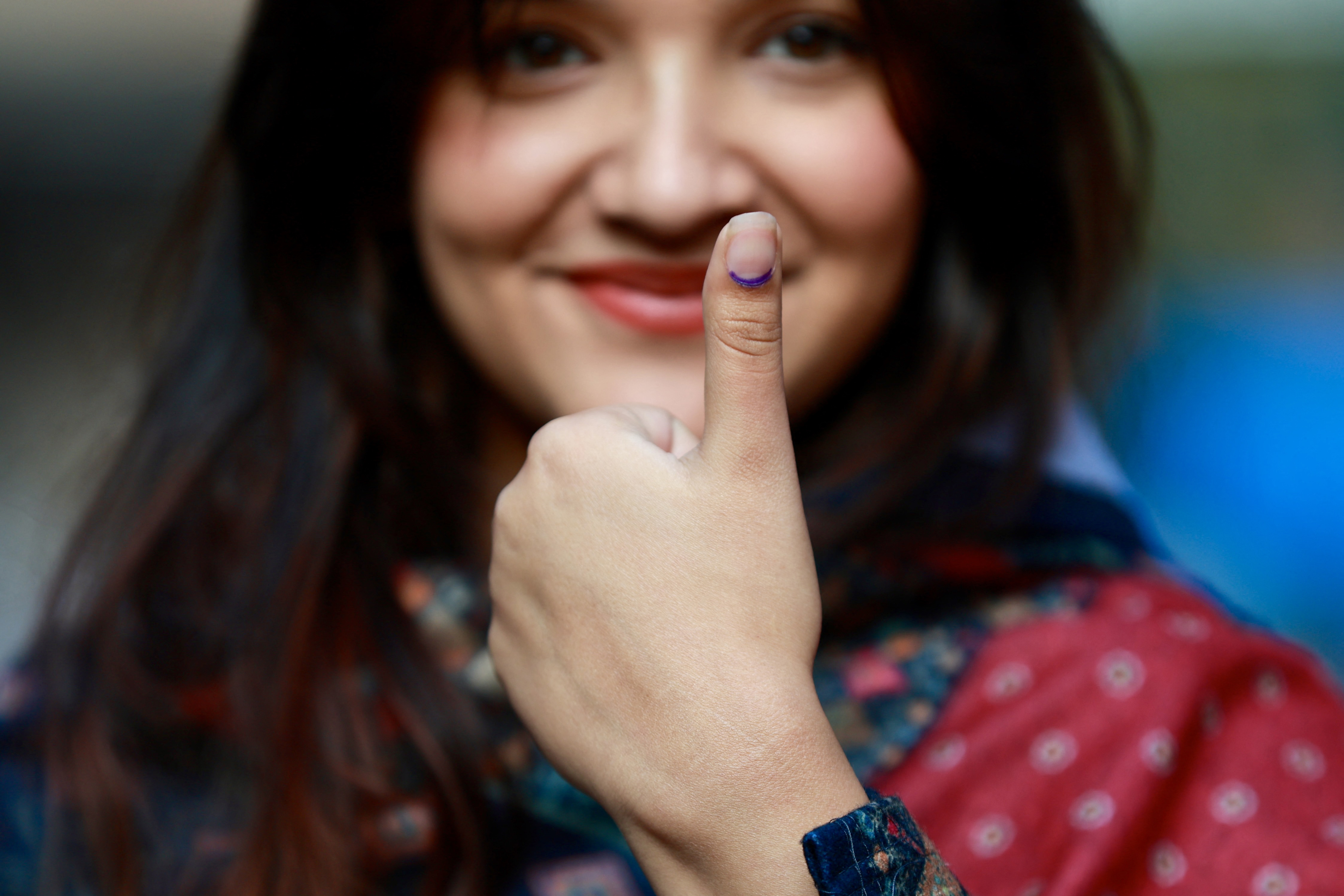 A voter shows her thumb with purple ink after casting her ballot.