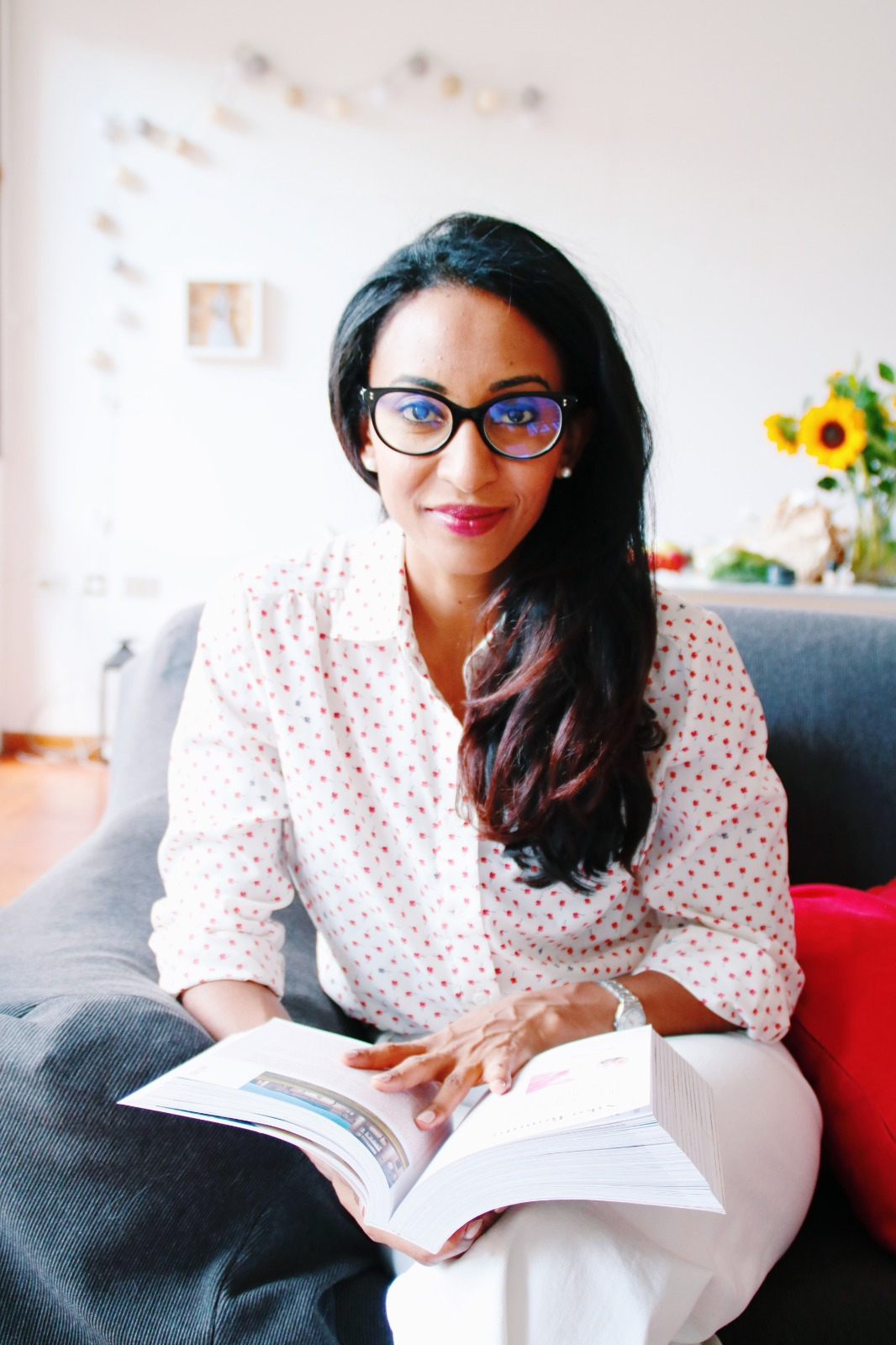 Linia Patel sitting on a couch and holding a book.
