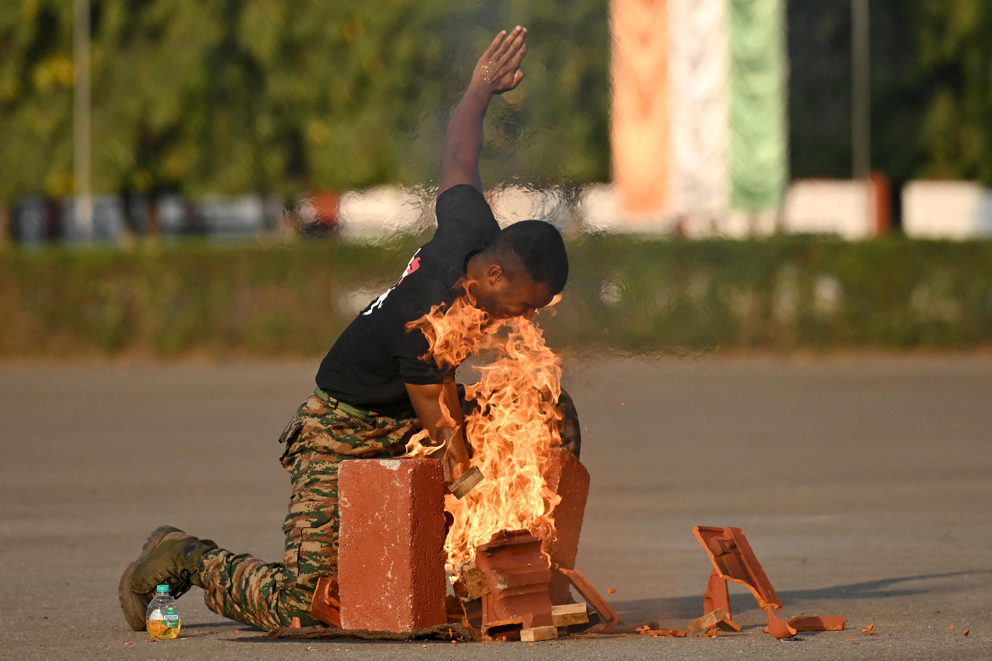 An Indian army cadet performing a stunt with fire and broken bricks.