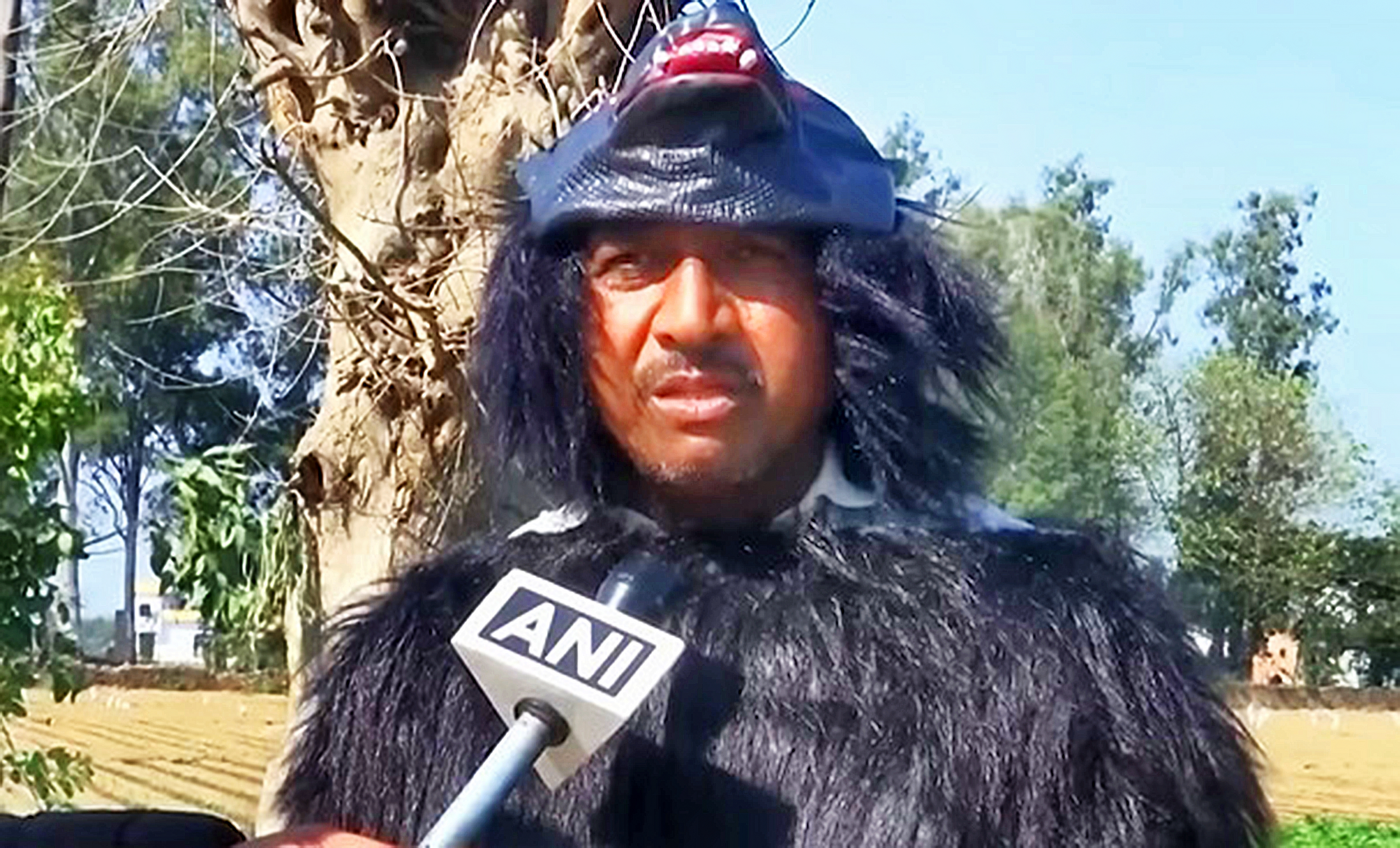 A farmer dressed in a bear costume holding an ANI microphone.