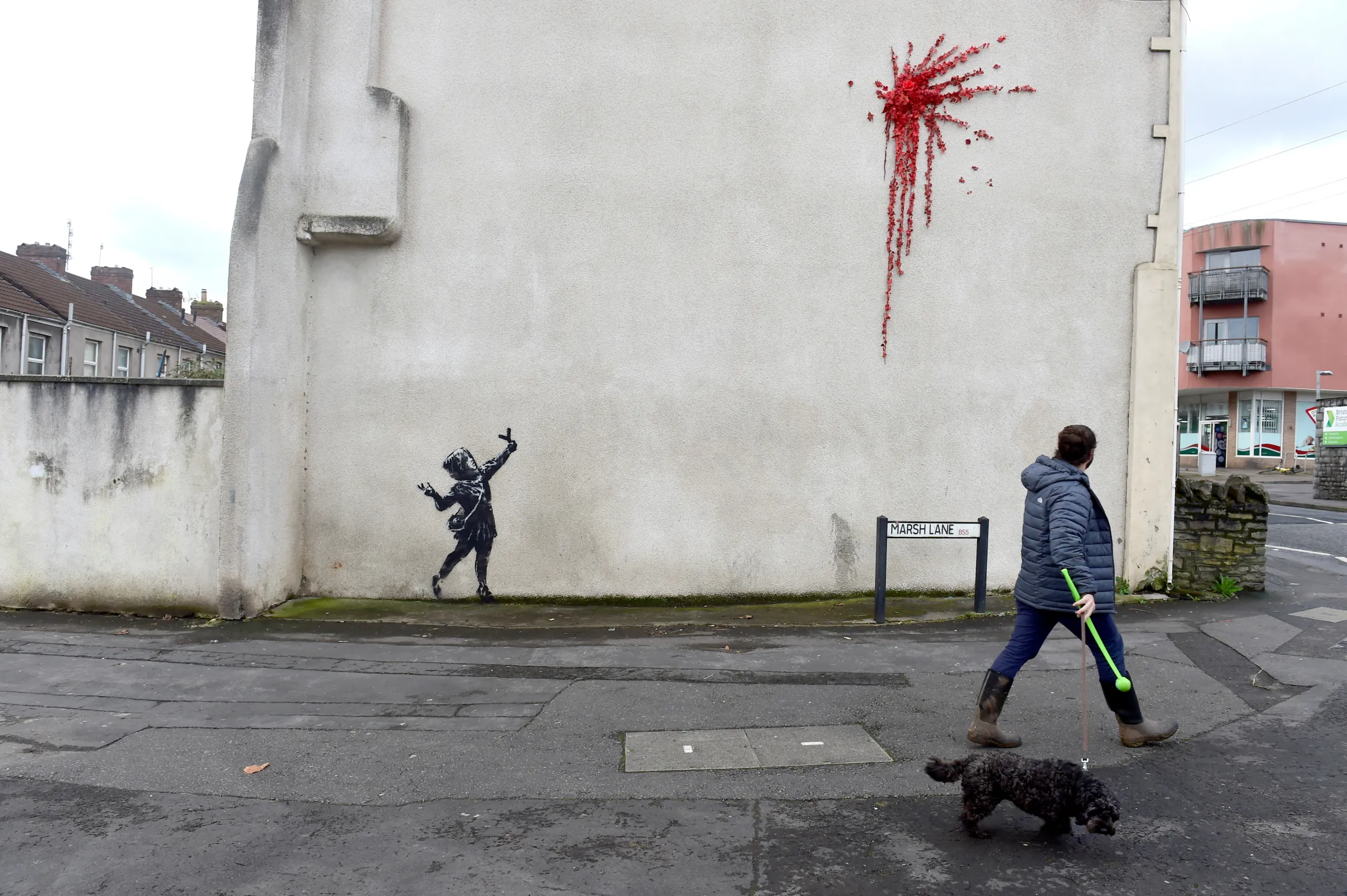 A Banksy mural depicting a girl releasing a burst of red leaves on a wall in Bristol.