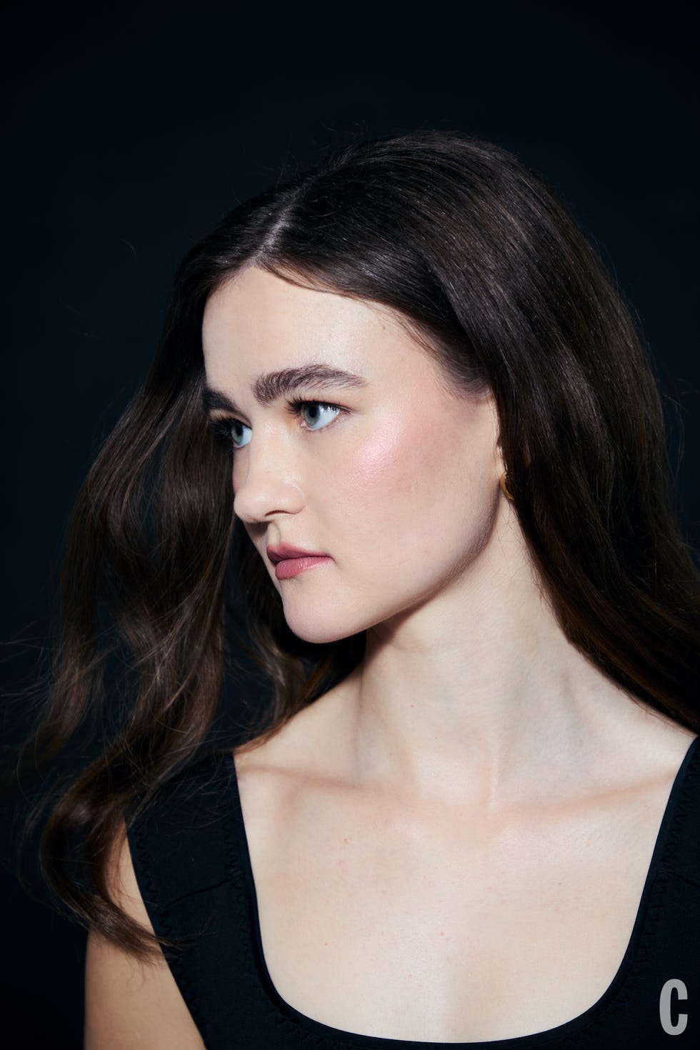 Female figure with long hair and a blurred face on a dark background.