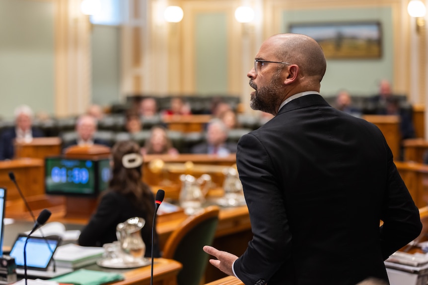 A man in a grey suit speaking in Queensland's state parliament.