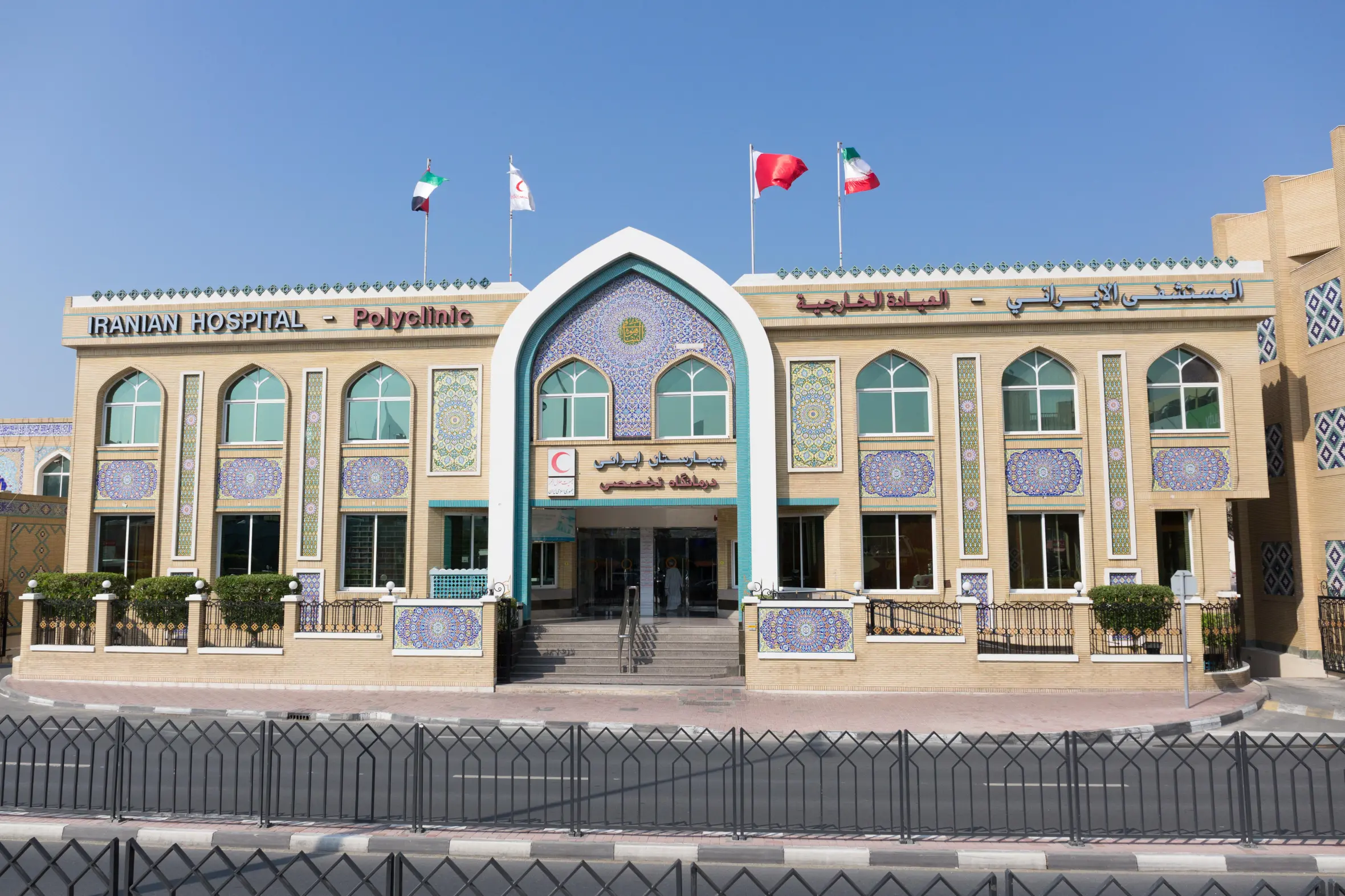 The Iranian Hospital in Dubai with flags of the UAE, the Red Crescent, Qatar, and Iran.
