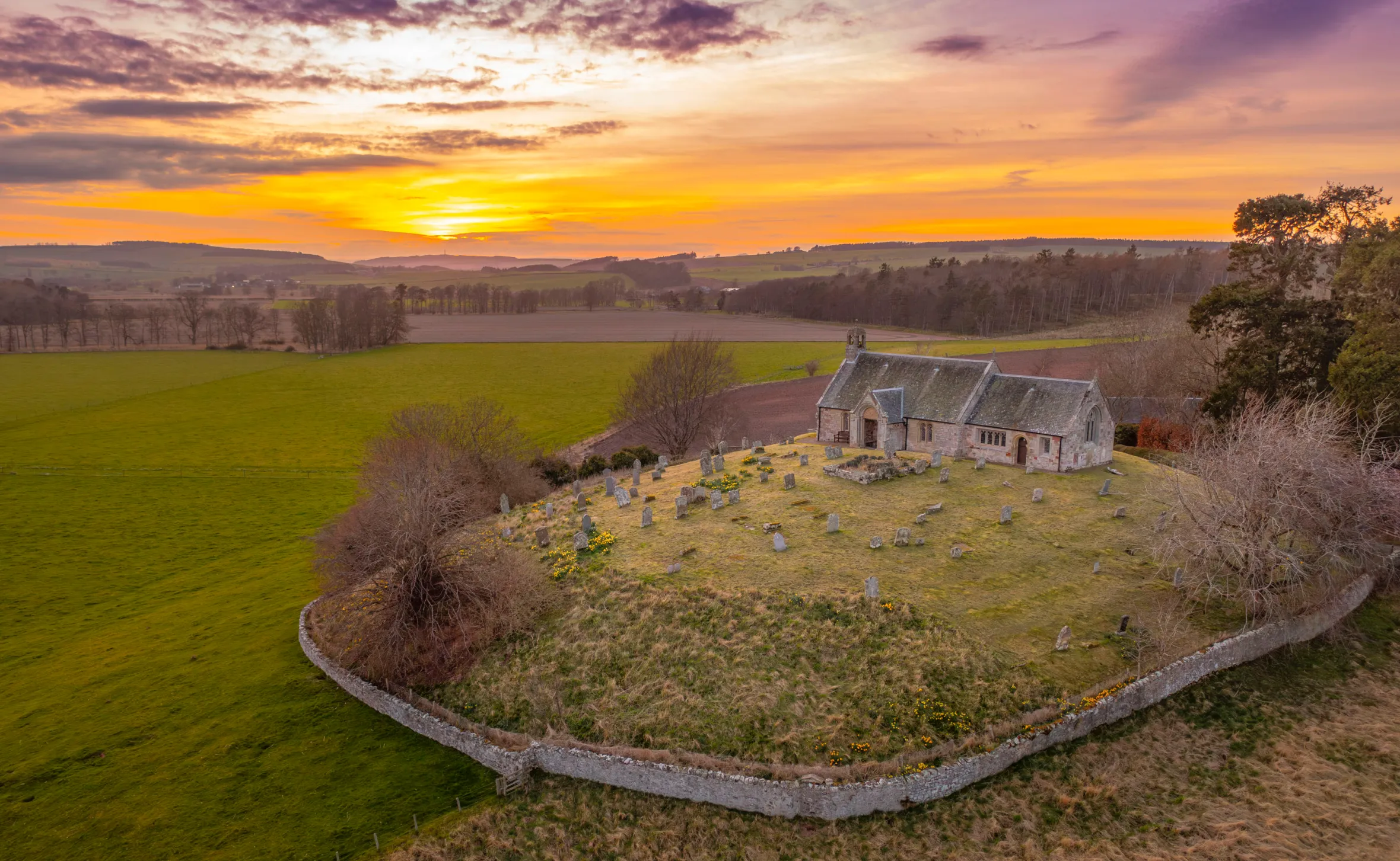 Linton Kirk, Scottish Borders, Scotland, under a vibrant orange and purple sunset.