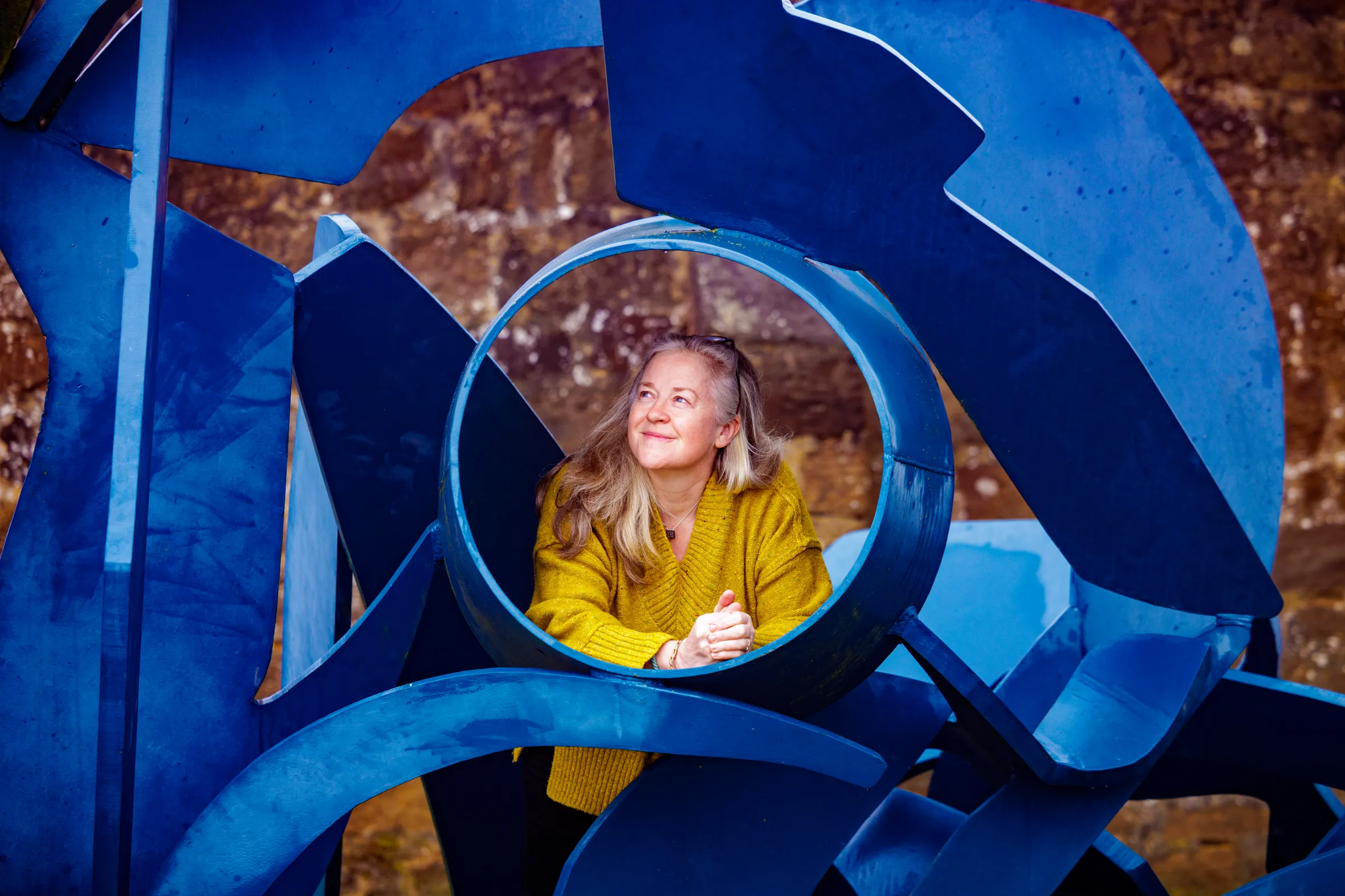 Sasha Jackson-Brown poses with the blue metal sculpture "Amphitrite" by Michael Lyon.