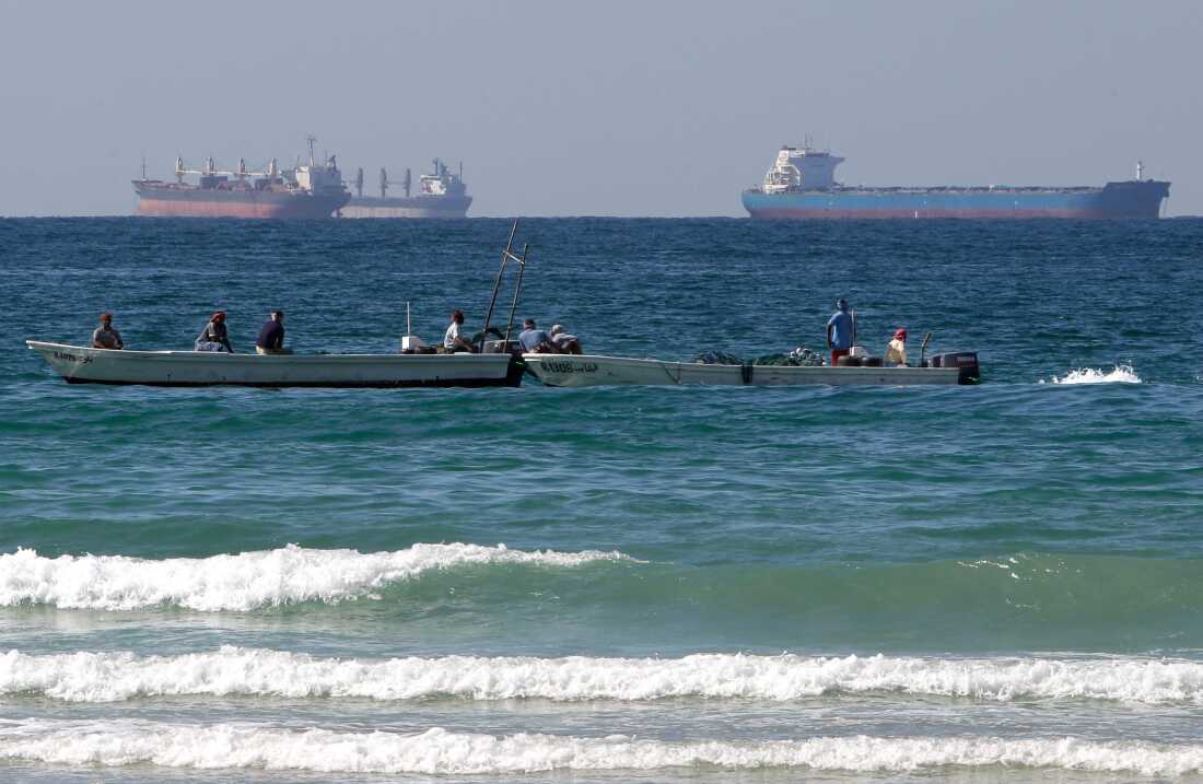 Fishermen work in front of oil tankers south of the Strait of Hormuz on Jan. 19, 2012, offshore of the town of Ras Al Khaimah in United Arab Emirates.