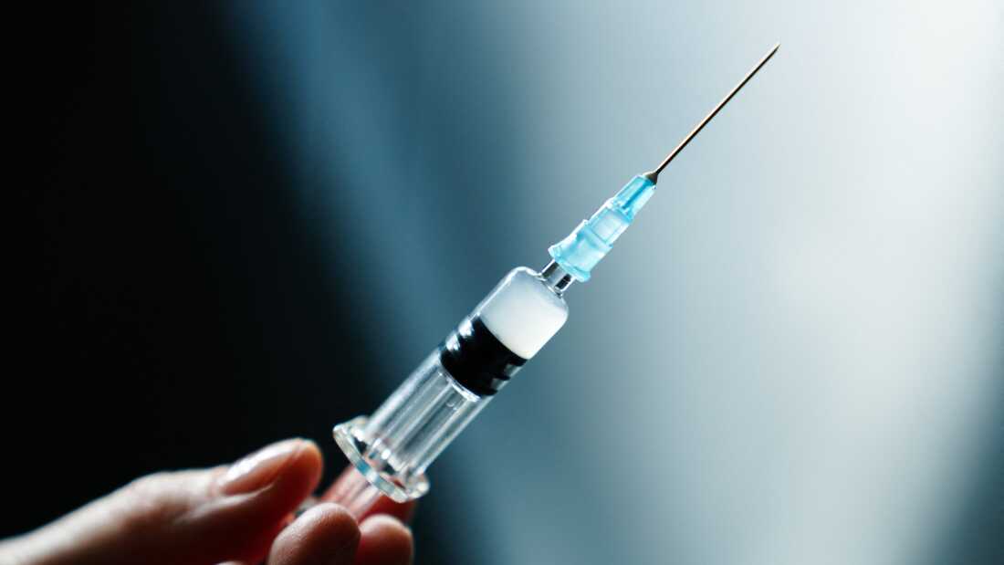 Illustration photo of a vaccine syringe in hand.